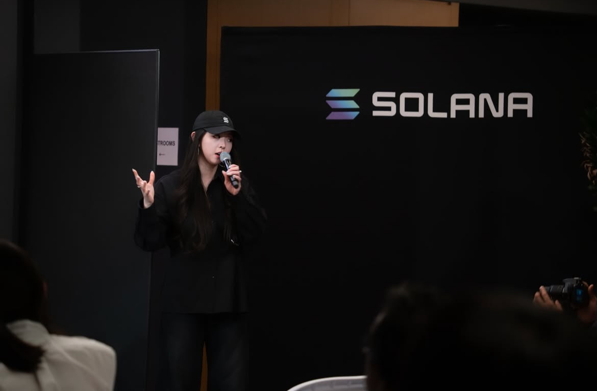 Speaker addressing a room in front of a Solana backdrop