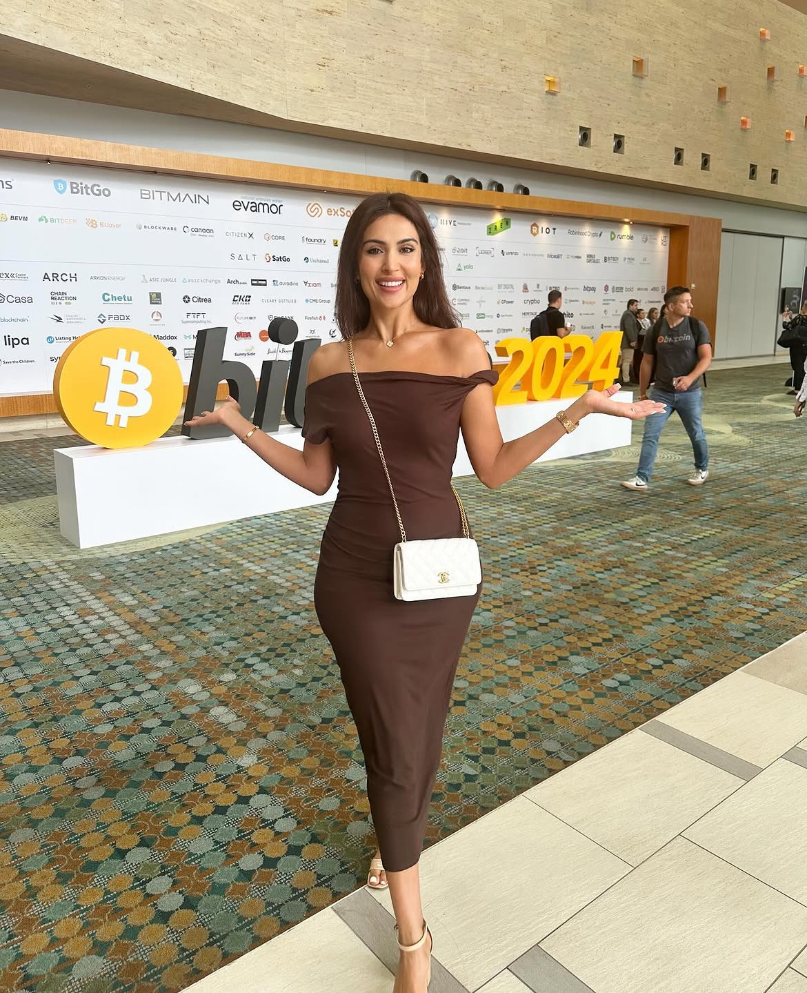 Attendee beside the Bitcoin 2024 lettering in front of a partner logo wall